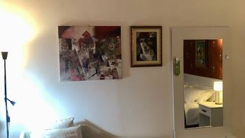 Una habitación de hotel con una cama, un aire acondicionado de pared y dos obras de arte enmarcadas.