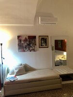 Una habitación de hotel con una cama, un aire acondicionado de pared y dos obras de arte enmarcadas.