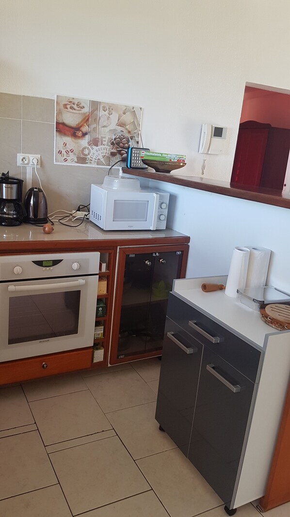 A compact kitchen with a built-in oven, a microwave, a coffee maker, and a small refrigerator.