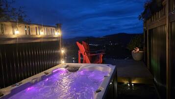 A hot tub with a view of the mountains at dusk.
