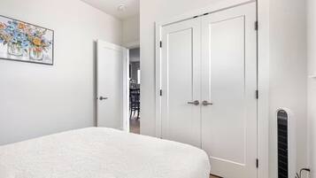A bedroom with a bed, a white door, and a radiator.