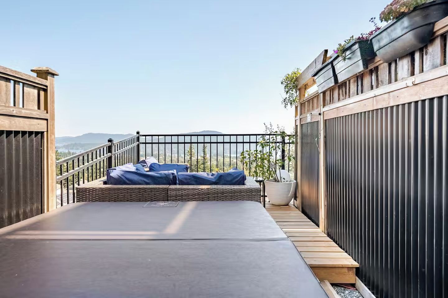 A rooftop terrace with a seating area, a railing, and a view of the landscape.