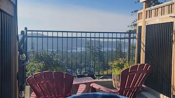 Relax on the balcony with a view of the surrounding mountains, trees, and serene water.