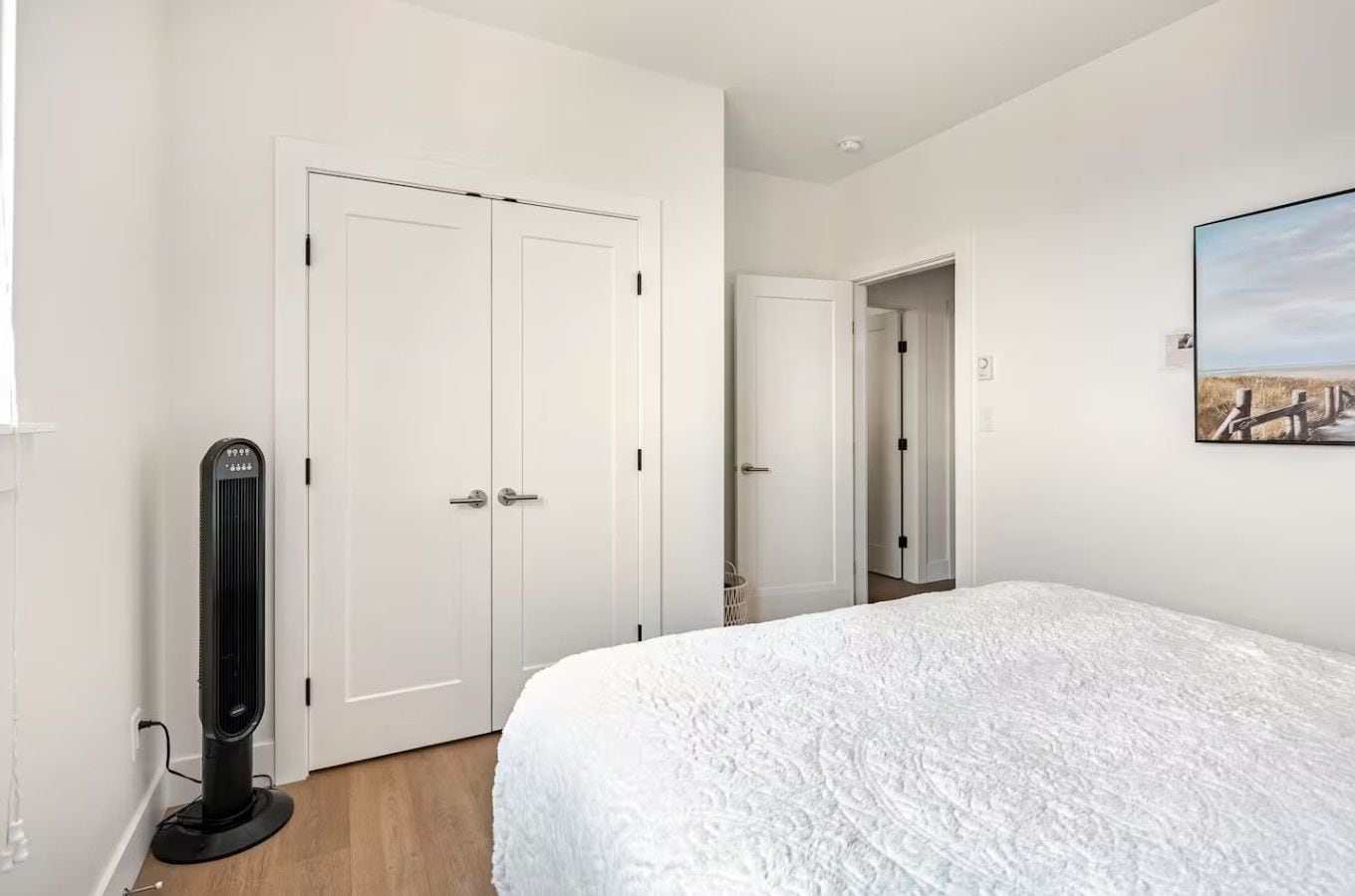 A bedroom with a bed, a standing heater, a wardrobe, and a painting on the wall.