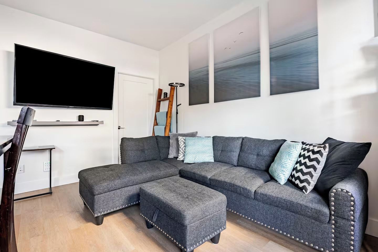 A modern living room with a sectional sofa, a flat-screen TV, and artwork on the walls.