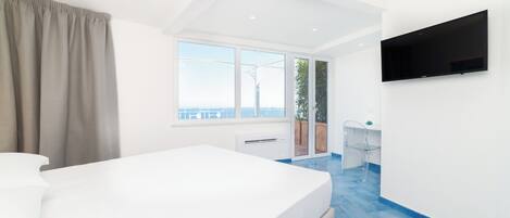 A modern bedroom with a large bed, a TV mounted on the wall, and a view of the outdoors.