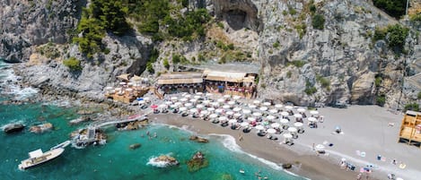 En la playa, playa de arena negra, sombrillas y toallas de playa 