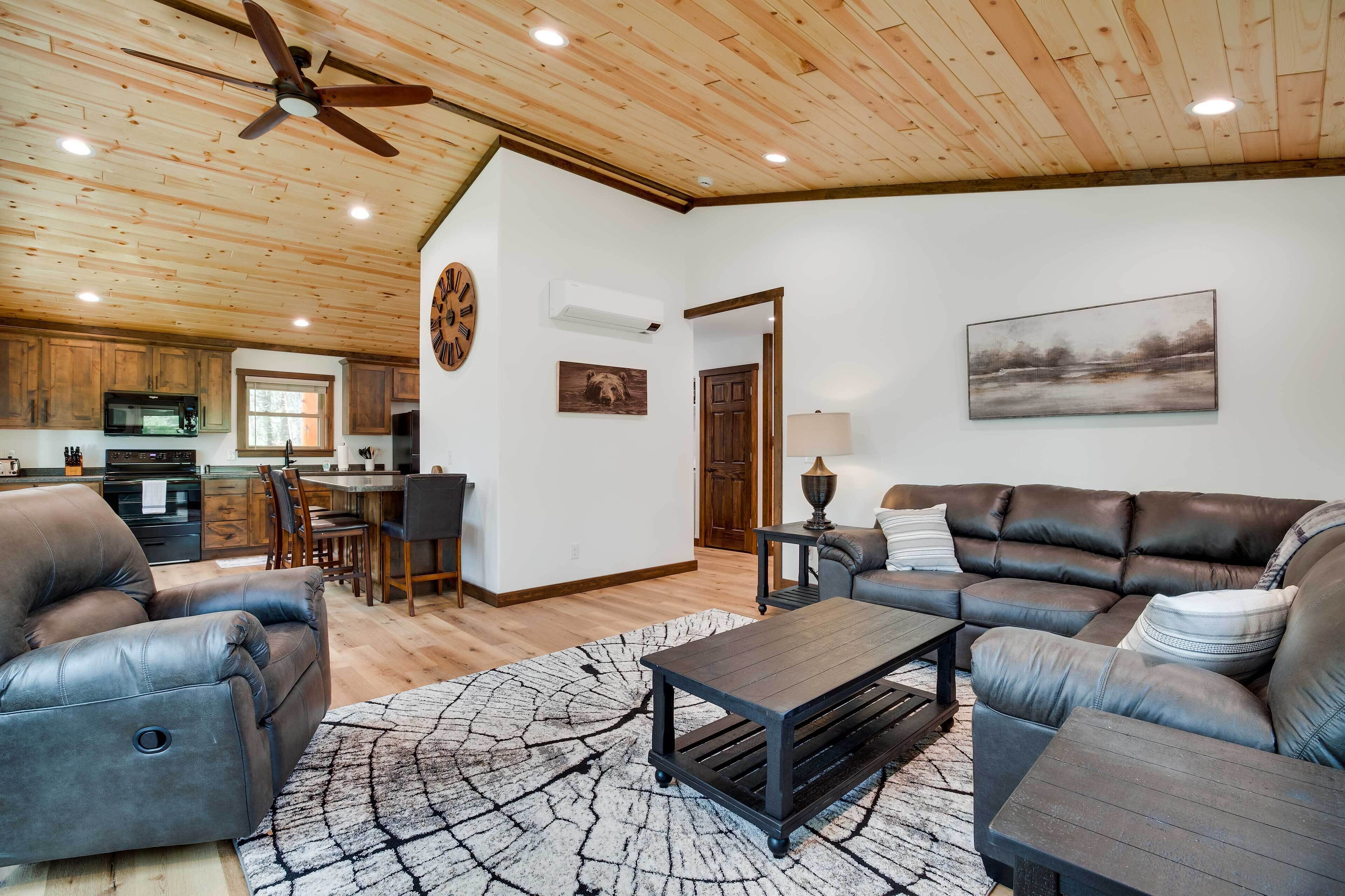 A spacious living room with a leather sofa, a coffee table, and a dining area with a wooden table and chairs.
