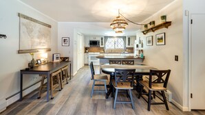A kitchen with a central island, wooden chairs, and a hanging light fixture. - Riverfront Condo Near Downtown Estes Park! (Estes Park)