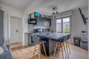 A modern kitchen with a central island, bar stools, and a view of the outside.