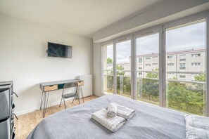 Une chambre à coucher avec un lit, un bureau et un téléviseur fixé au mur.