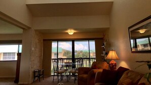 A spacious living area with a balcony, a dining table with chairs, and a sofa. - Ocean Village South Floridas Premier Gated Ocean Front Resort with Pool and Golf (Hutchinson Island)