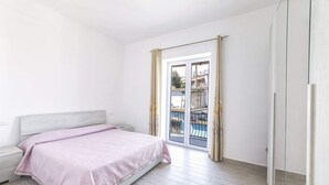 A bedroom with a bed, a nightstand, a wardrobe, and a sliding glass door to a balcony. - Agave House (Forio)