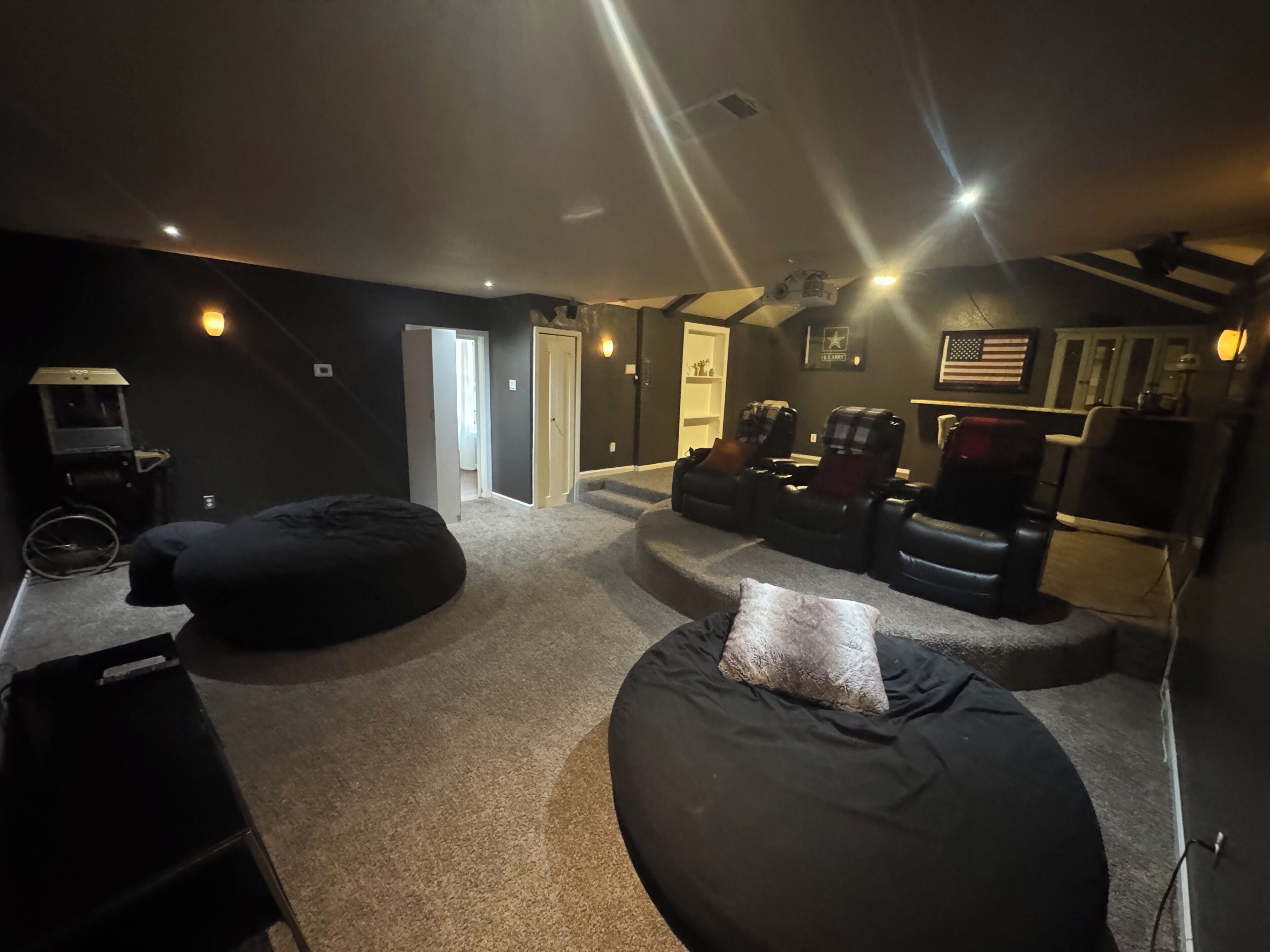 A home theater room with a large screen, reclining chairs, and a carpeted floor.