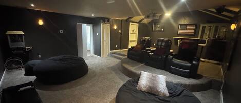 A home theater room with a large screen, reclining chairs, and a carpeted floor.
