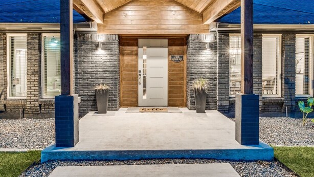 A modern house with a stone facade, a wooden porch, and a well-lit entrance. - Heated Pool, Putting Green, Movie Theater and more! 4 bed/3 bath (Dallas)