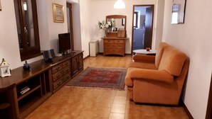 Ein Wohnzimmer mit einer Couch, einem Fernseher auf einer Holzkommode, einem Schminktisch und einem Spiegel.