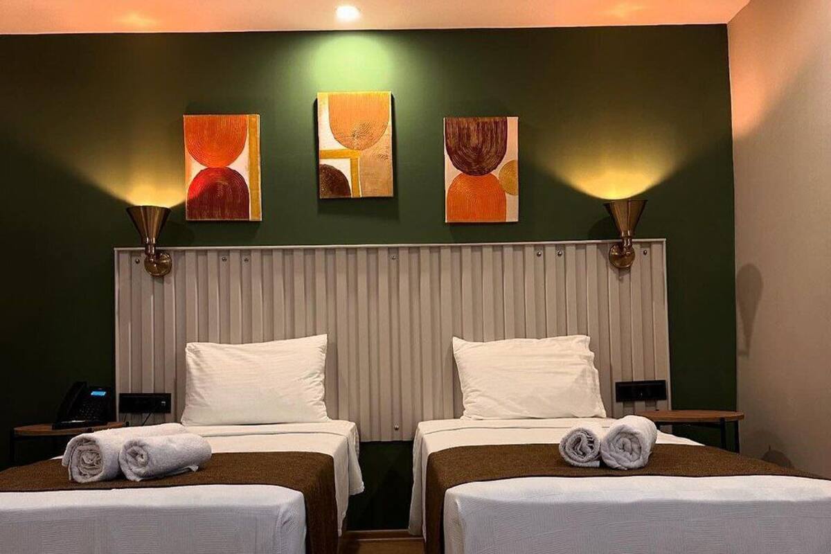 A hotel room with two beds, a large window, and a wall-mounted artwork.