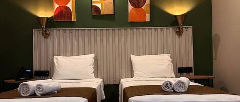 A hotel room with two beds, a large window, and a wall-mounted artwork.
