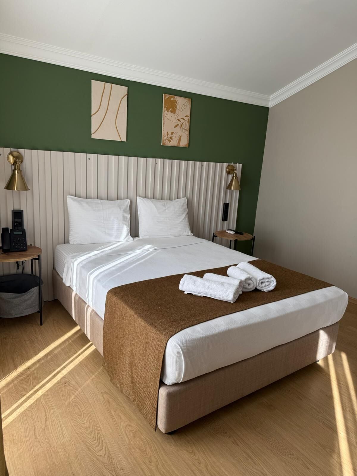 Un cuarto de hotel con una cama grande, dos mesitas de noche, una lámpara y arte en la pared.