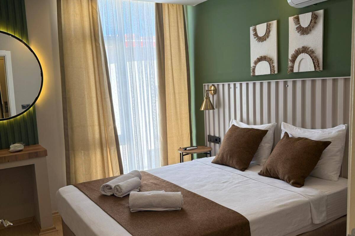 A hotel room with a large bed, a bedside table, a mirror, and an air conditioning unit.