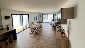 A spacious, modern kitchen with a large dining area, wooden flooring, and large windows. - Villa Climatiséeavec Piscine Chauffee, Proche mer (Angoulins)