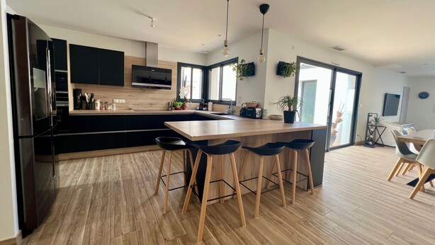 A modern kitchen with a central island, bar stools, and a dining area with chairs. - Villa Climatiséeavec Piscine Chauffee, Proche mer (Angoulins)