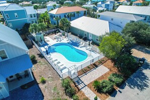 Un quartier résidentiel doté d’une piscine entourée de chaises longues et d’une terrasse délimitée par une clôture.