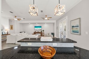 A modern kitchen with a central island, black granite countertops, and a wooden bowl.