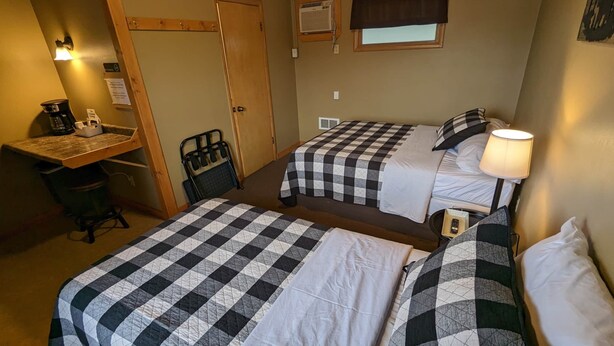 Une chambre avec deux lits, un bureau, une chaise et une fenêtre.