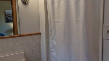 Un baño con lavamanos blanco, espejo y cortina de ducha.