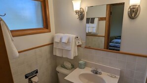 A bathroom with a toilet, sink, and mirror. There are towels hanging on the wall and a sign indicating the use of toilet paper. - Chip-Wa Lodging Room 5 (Hunter)