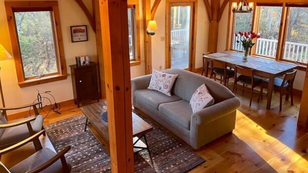 Un interior acogedor de cabaña con un sofá, una mesa de comedor y sillas.