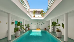A swimming pool with potted plants and a skylight.