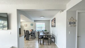 A modern kitchen with a dining area, featuring a large window, a clock, and a welcome sign. - Relaxing Apartment Close to the Beach ! (Cape Canaveral)