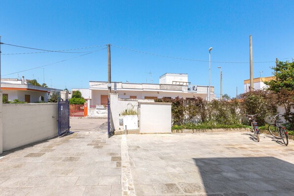 Un patio con suelo empedrado, una reja y un edificio de techo plano al fondo.