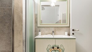 A bathroom with a glass shower enclosure, a sink with a decorative cabinet, and a mirror with a light fixture above it. - Canaiolo holiday home with mini-pool in the center of Greve in Chianti (Greve in Chianti)