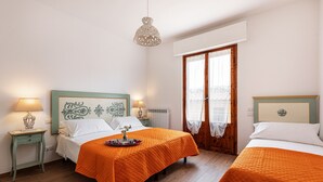 A hotel room with two beds, wooden flooring, a window with a view, and a decorative ceiling light. - Canaiolo holiday home with mini-pool in the center of Greve in Chianti (Greve in Chianti)