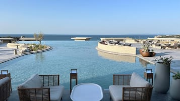 Un espace aménagé au bord de la piscine, avec des meubles en osier, des plantes en pot et une vue sur la mer.