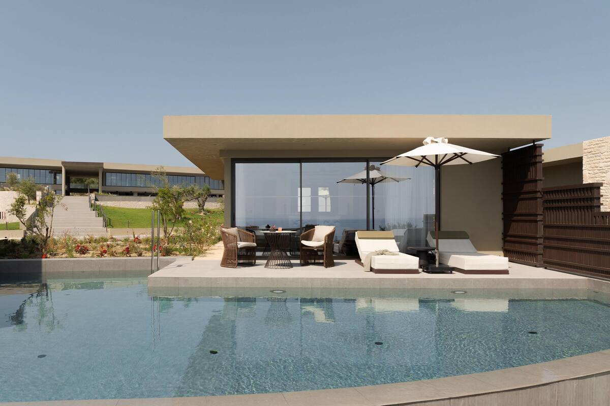 A modern outdoor pool area with a seating arrangement and a covered section.