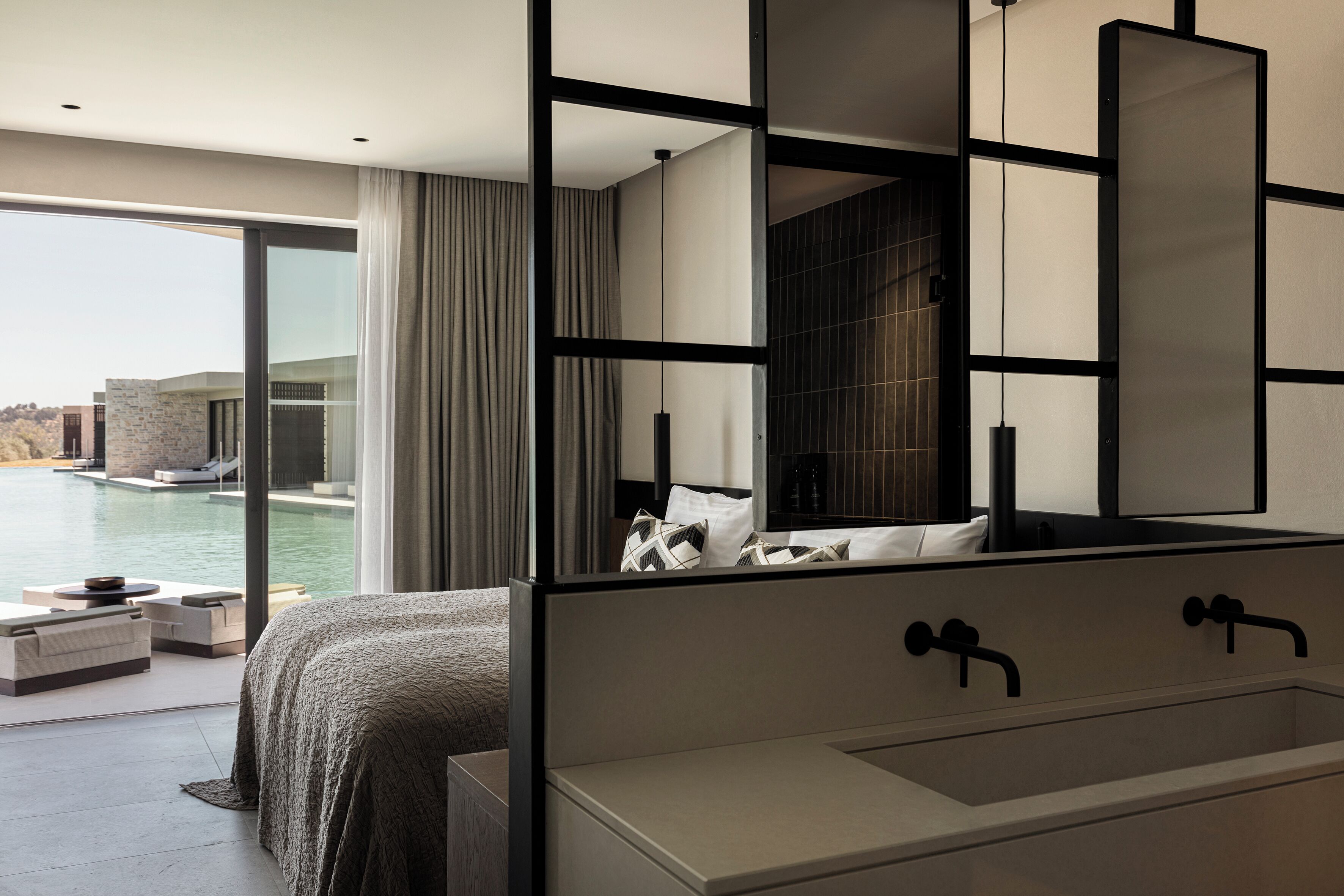 A modern bedroom with a large bed, a built-in bathtub, and a view of a swimming pool.