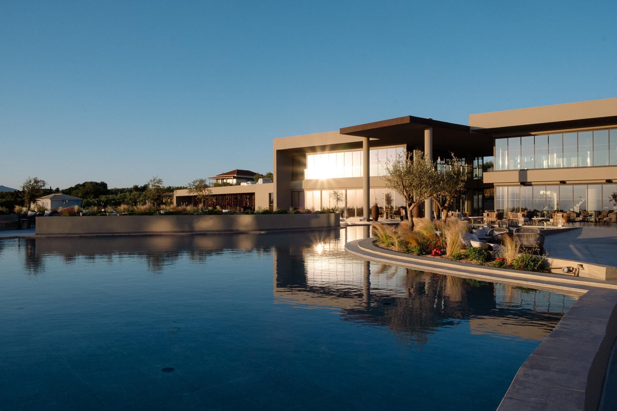 Un hôtel moderne doté d’une piscine, d’un espace extérieur aménagé et offrant une vue dégagée sur le paysage environnant.