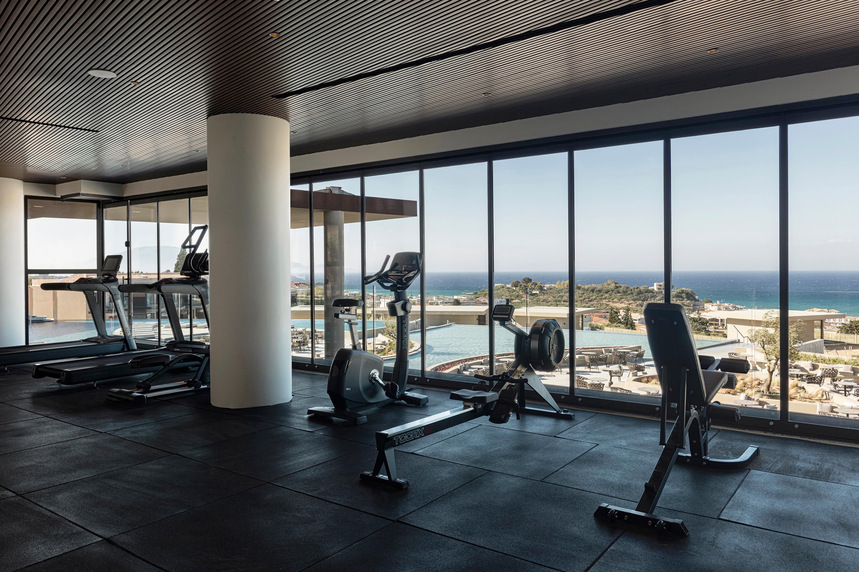 Une salle de sport équipée de matériel d’exercice et dotée de grandes fenêtres donnant sur un paysage magnifique.