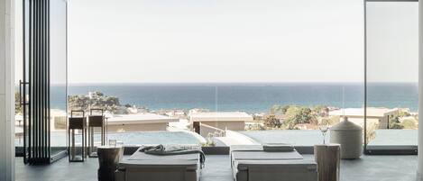 A modern room with two beds, a view of the sea, and a large window.