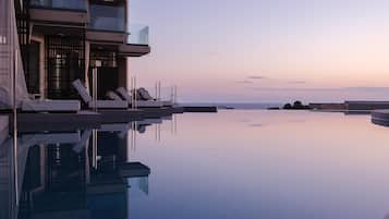 Et moderne hotel med en pool, der spejler bygningen og himlen.