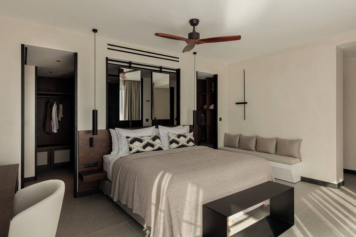 A modern bedroom with a bed, bedside tables, a ceiling fan, and a walk-in closet.