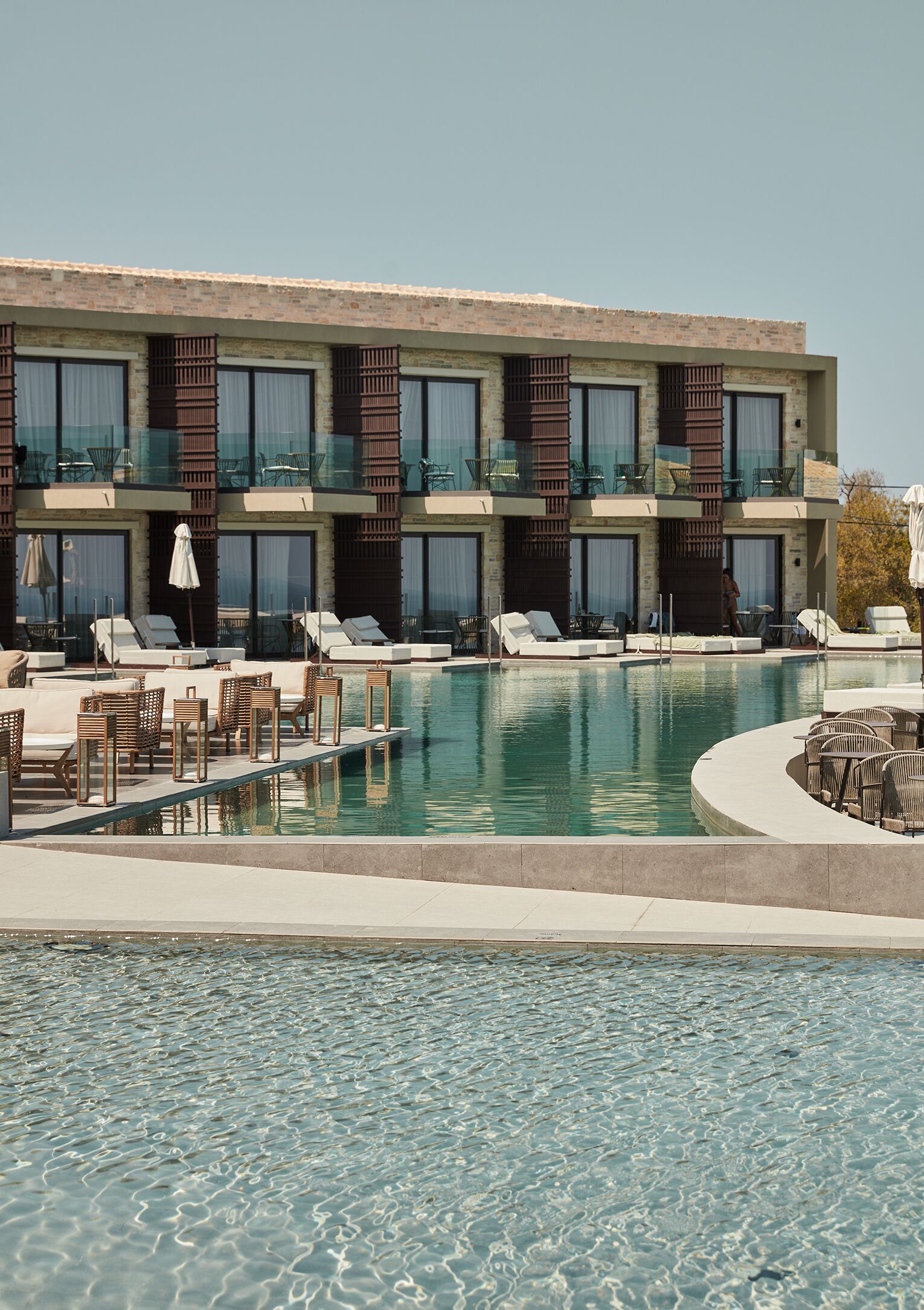A hotel with a pool area, including lounge chairs and umbrellas.