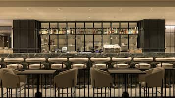 Un espace bar offrant différentes options de sièges, une sélection complète de boissons alcoolisées et un aménagement intérieur moderne.