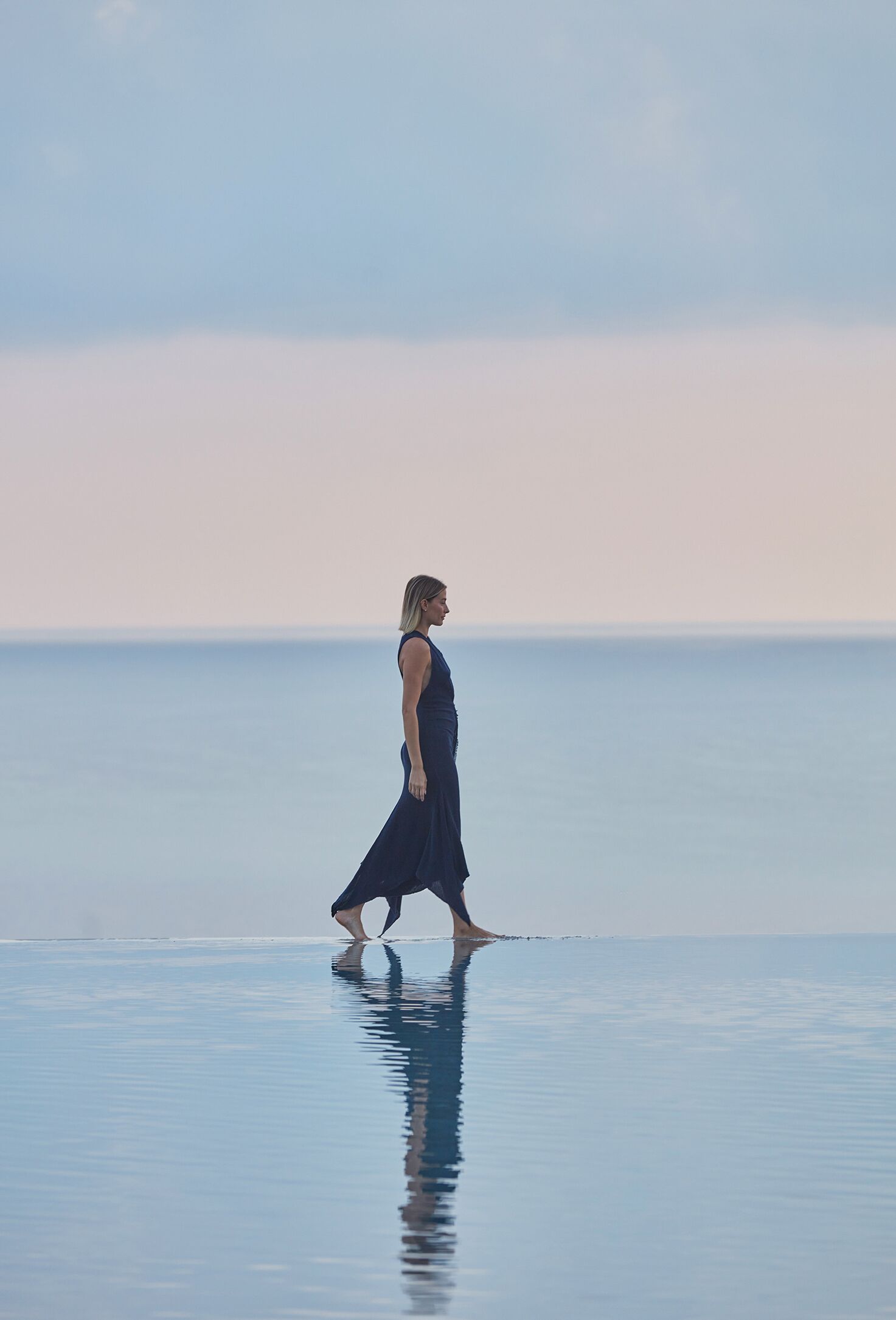 Eine Person geht auf einer reflektierenden Fläche in der Nähe von Wasser.