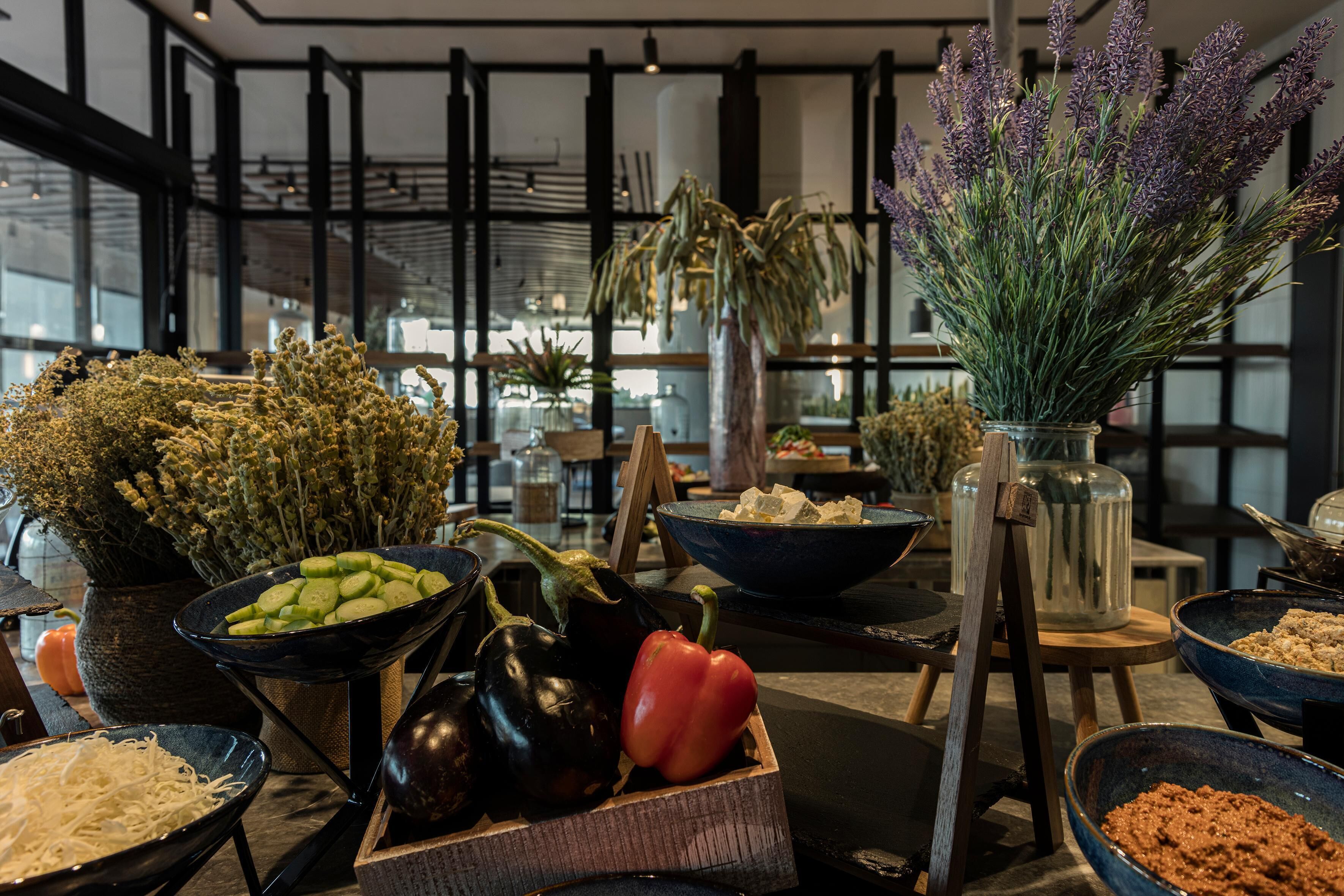 A variety of fresh vegetables and herbs displayed in bowls and containers, suggesting a focus on fresh ingredients.